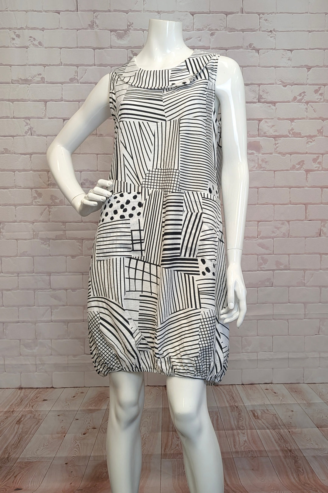 VARIATIONS Spring 2025 This eye-catching abstract print, woven dress features a light cowl neck and an elastic bubble hem, all in just above the knees length.