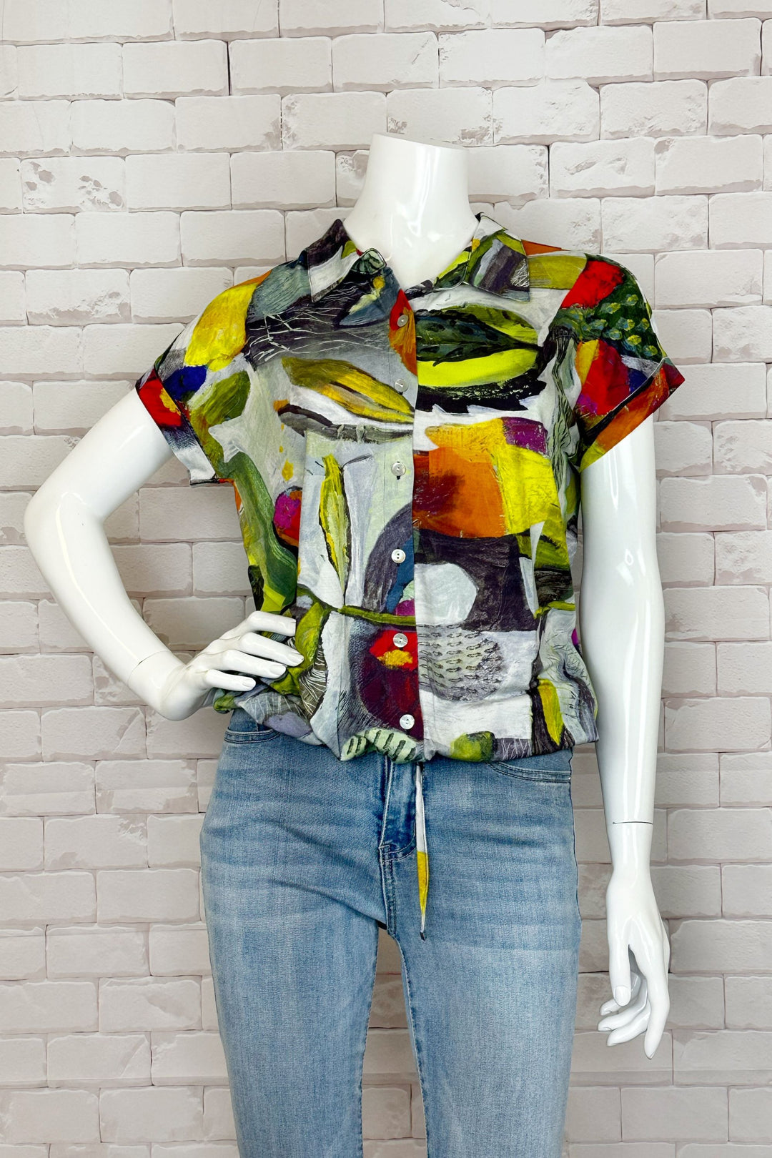 This Botanica blouse is a vibrant and versatile piece, featuring short sleeves, front buttons, a tie waist and a capitivating bold floral abstract pattern.