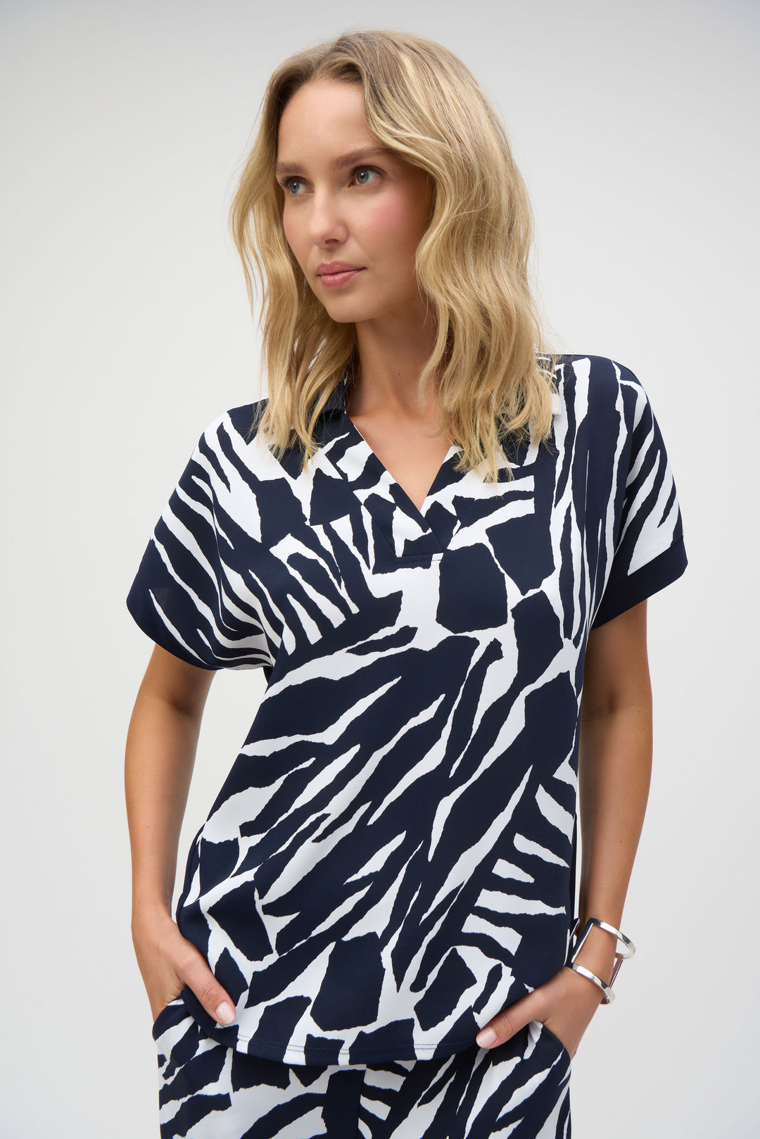 Joseph Ribkoff Spring 2025 Made with silky knit fabric, this top features a looser fit and short dolman sleeves for a relaxed resort look!