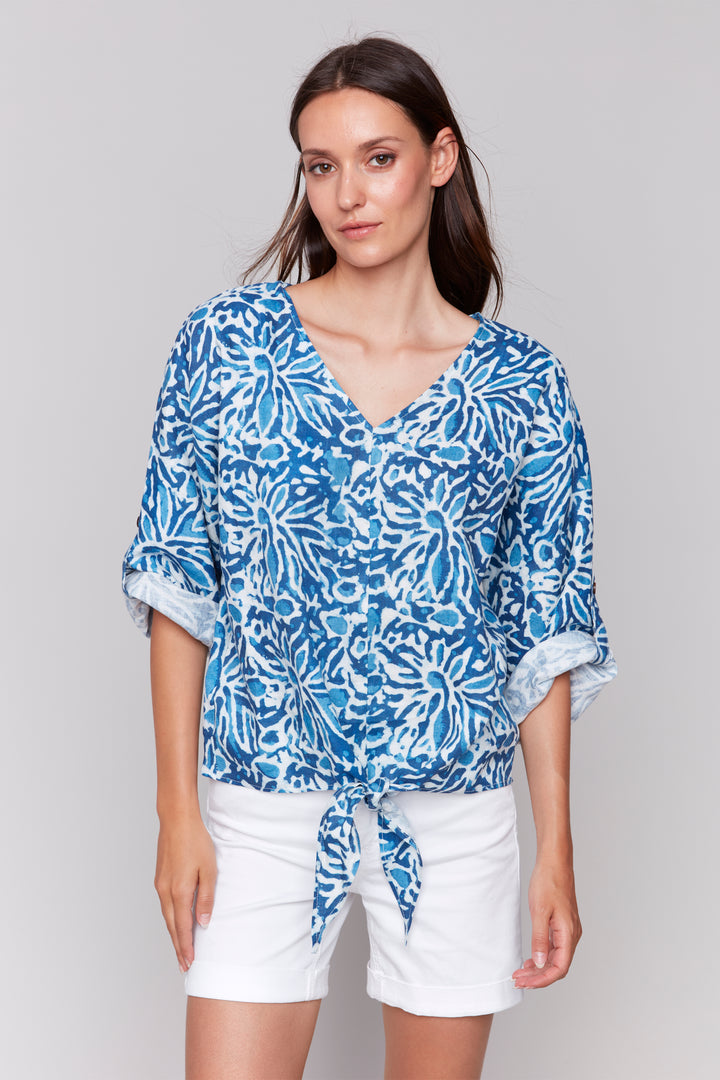 Charlie B Spring 2025  Featuring a stunning print and playful tie knot front hem, this top will add a pop of colour to any outfit. With dolman 3/4 roll up sleeves -shorts or capris. 
