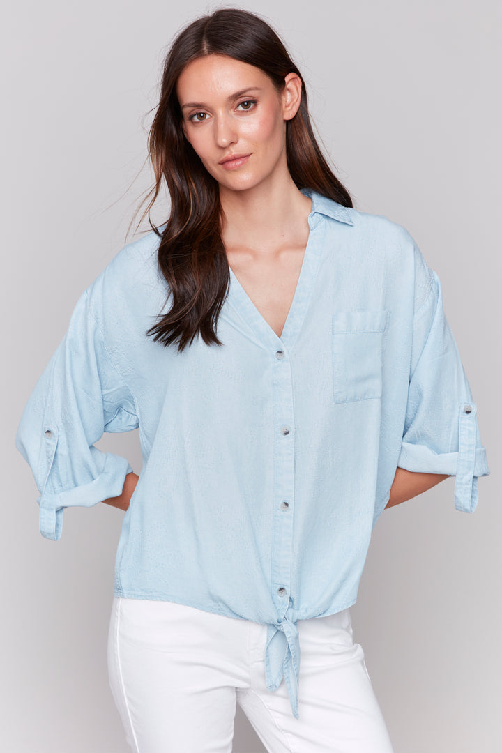 Charlie B Spring 2025 This classic collar shirt features a full front button design with a cute tie knot at the hem. Roll up the 3/4 length button cuff sleeves for a versatile look.