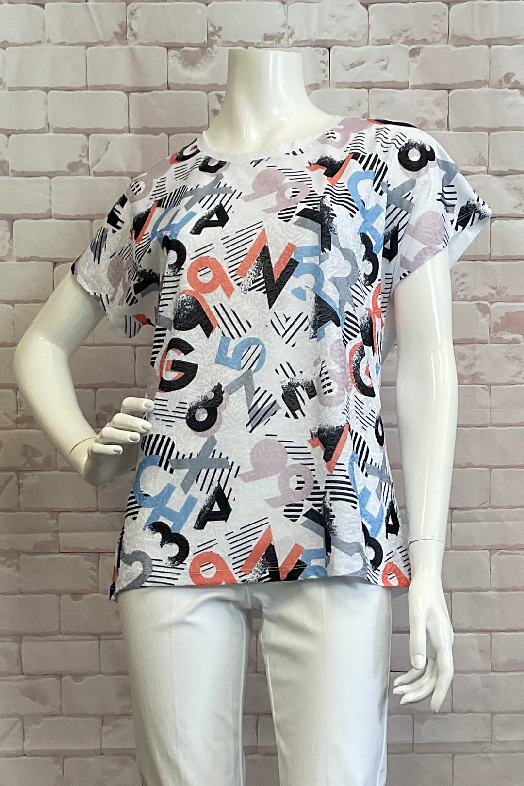 Ness Spring 2025 Made from a stretch fabric, this top features a playful mix print of letters & numbers. The double stitch cuffs and hemline add durability, while the contrast white back and round neck add a touch of uniqueness and style.