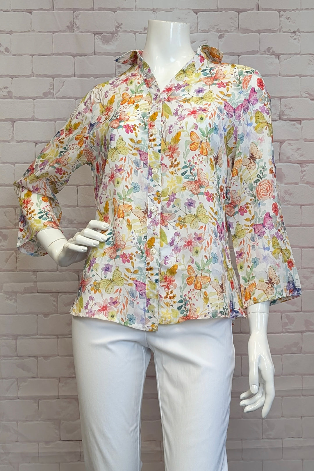 VARIATIONS Spring 2025 The cheerful butterfly print adds a touch of whimsy, while the button roll-up cuffs and collared v-neck make it versatile for dressing up or down.