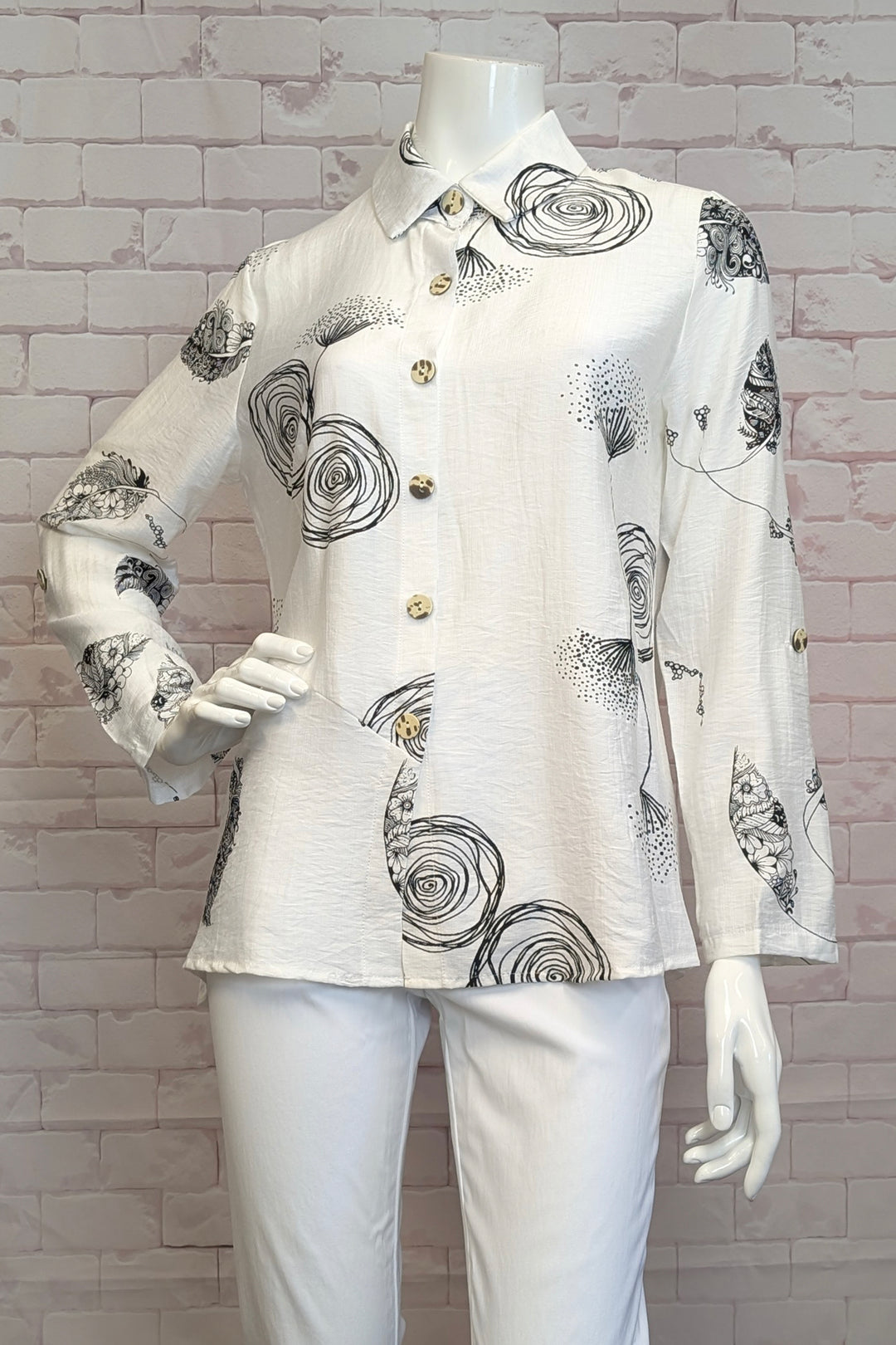 VARIATIONS Spring 2025 This piece doubles as a light jacket in the summer, with full length sleeves and a classic collar. The front button design adds a touch of sophistication to this exclusive blouse.