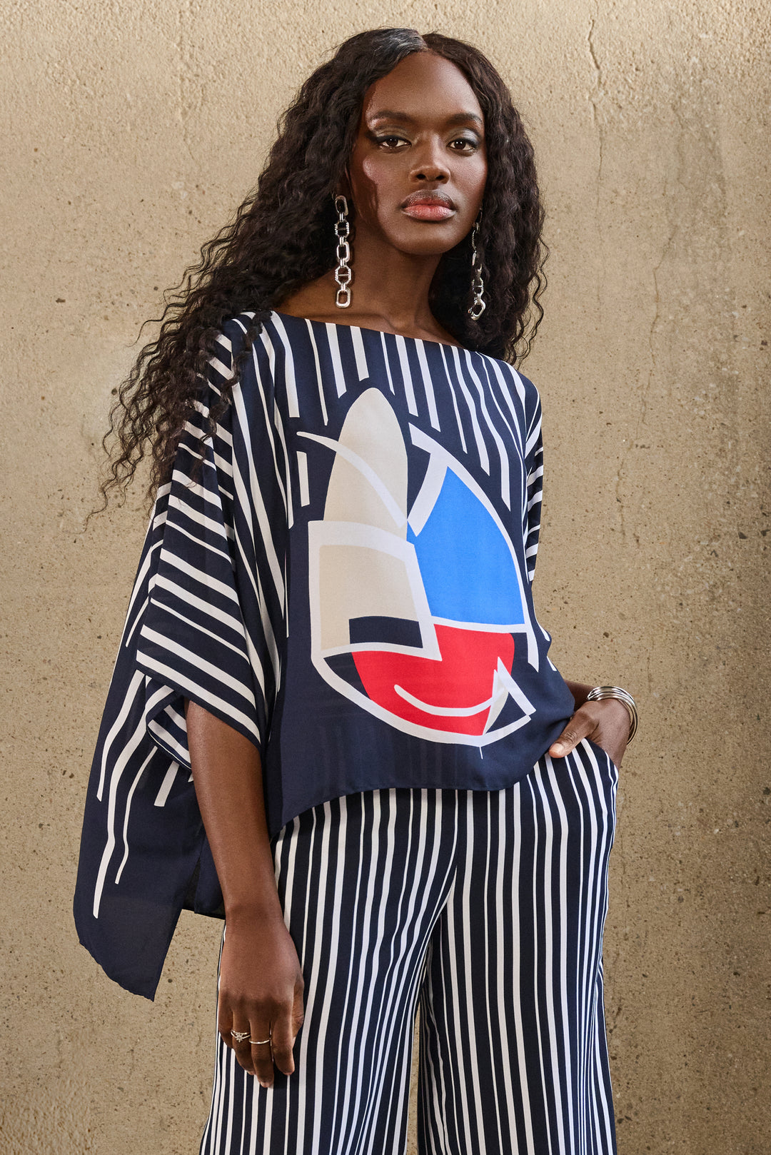 Joseph Ribkoff Spring 2025  Its loose and relaxed fit, dolman sleeves and boat neckline will keep you looking effortlessly stylish. The neat abstract print is sure to turn heads, making it the perfect top for any occasion. 
