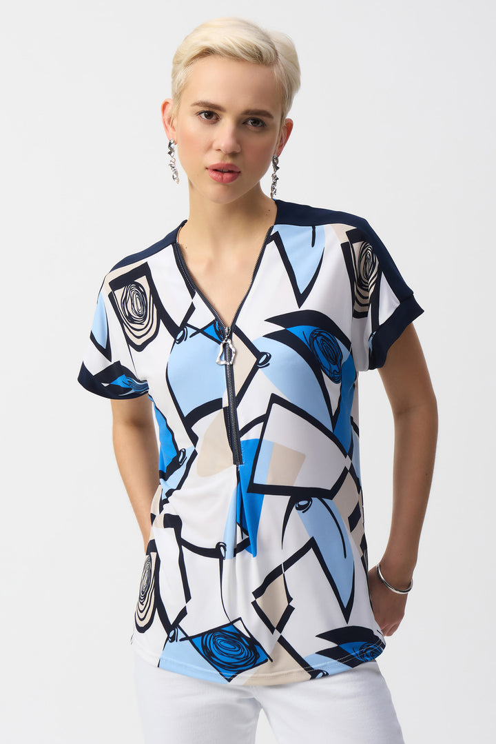 Joseph Ribkoff Spring 2025 Designed with short sleeves and side cut slits, it offers comfort and style, making it ideal for layering under a blazer for a polished look. The front pleat adds subtle texture, enhancing its refined appeal.