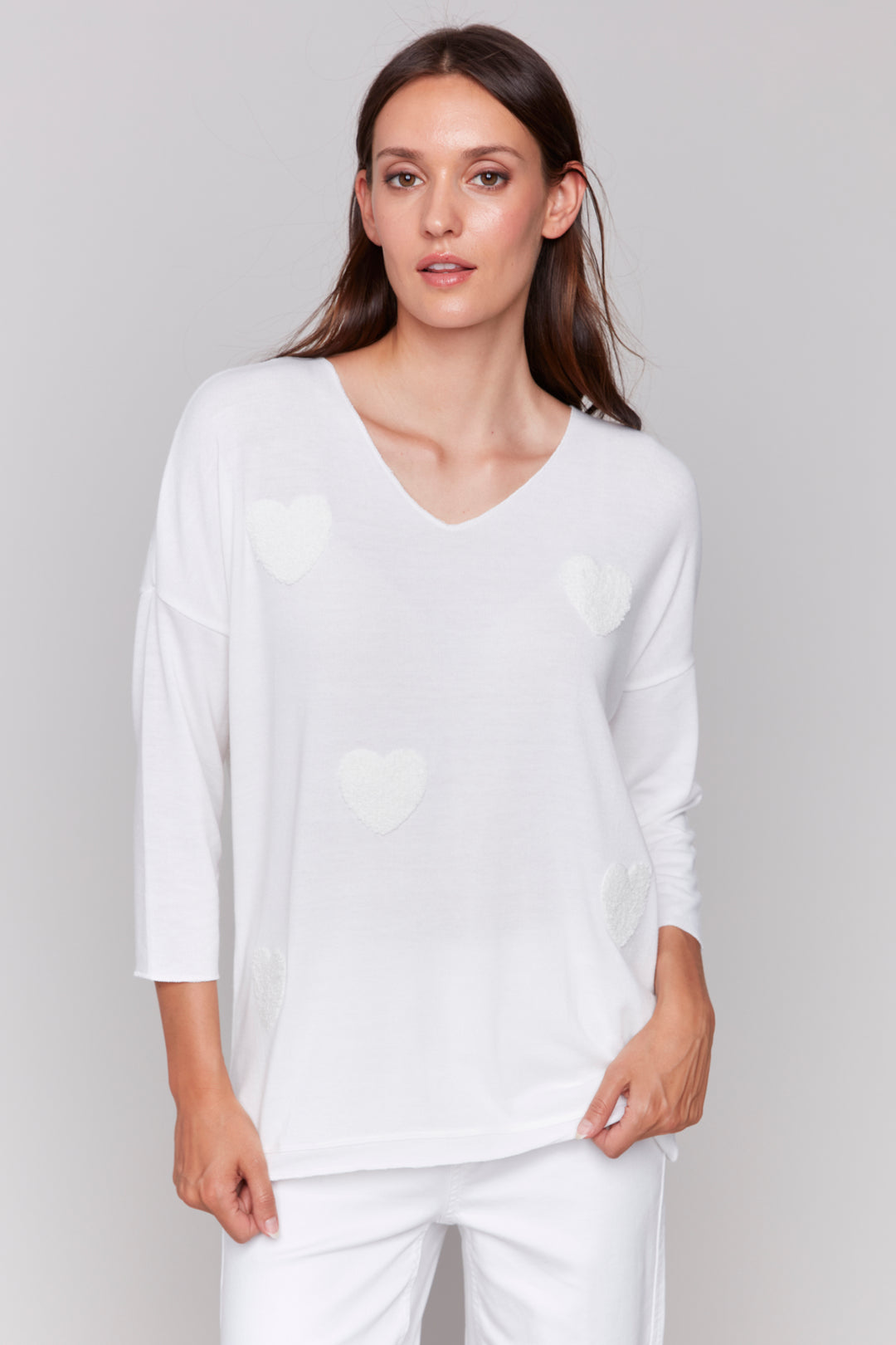 Charlie B Spring 2025  Crafted from a light, feather-like knit, this sweater top features a soft cut contrast v-neck, drop shoulder 3/4 length sleeves, and adorable stitched fuzzy hearts on the front. 