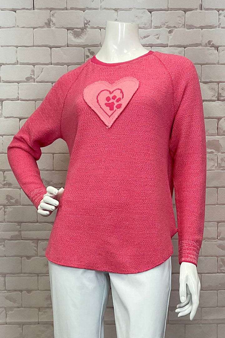 Cotton Country Spring 2025  With a curved hemline and light knit fabric, this top offers a flattering fit. The heart paw print will melt your heart while the raglan shoulder detail adds a nice touch. 