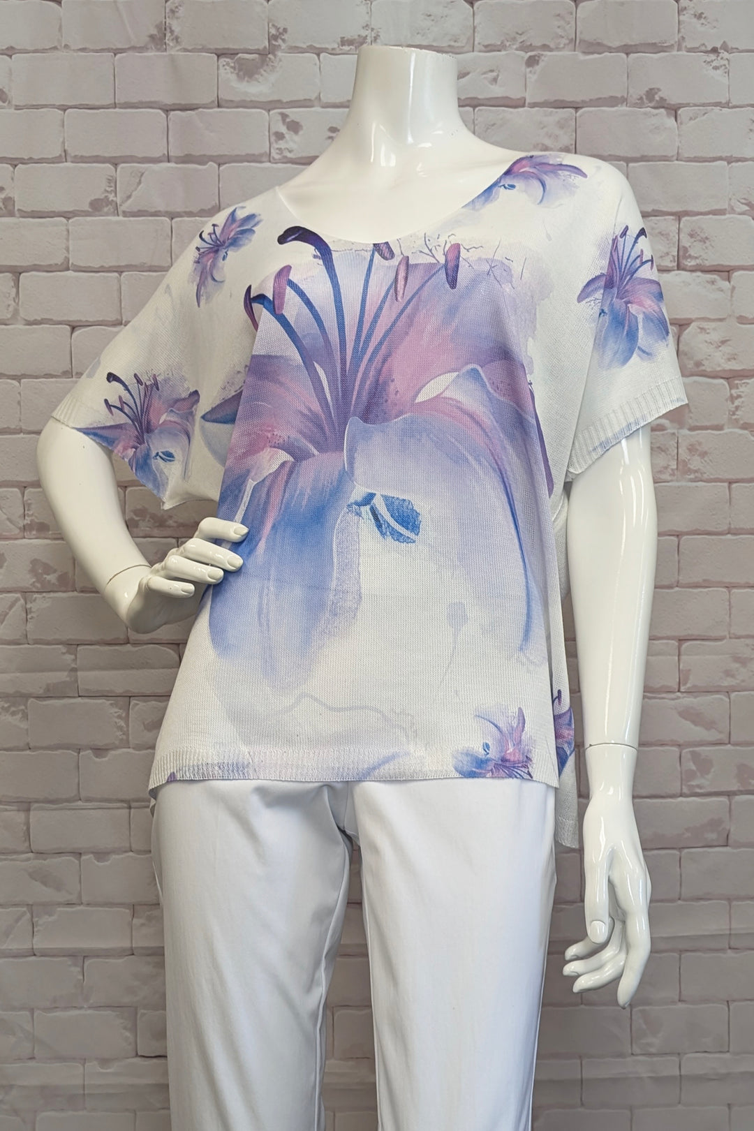 ANGELA MARA Spring 2025 Featuring a vibrant floral print and a slightly loose fit, this top offers both comfort and eye-catching appeal. Its short sleeves make it perfect for warm days, while pairing beautifully with capris or shorts for a fresh, casual look.