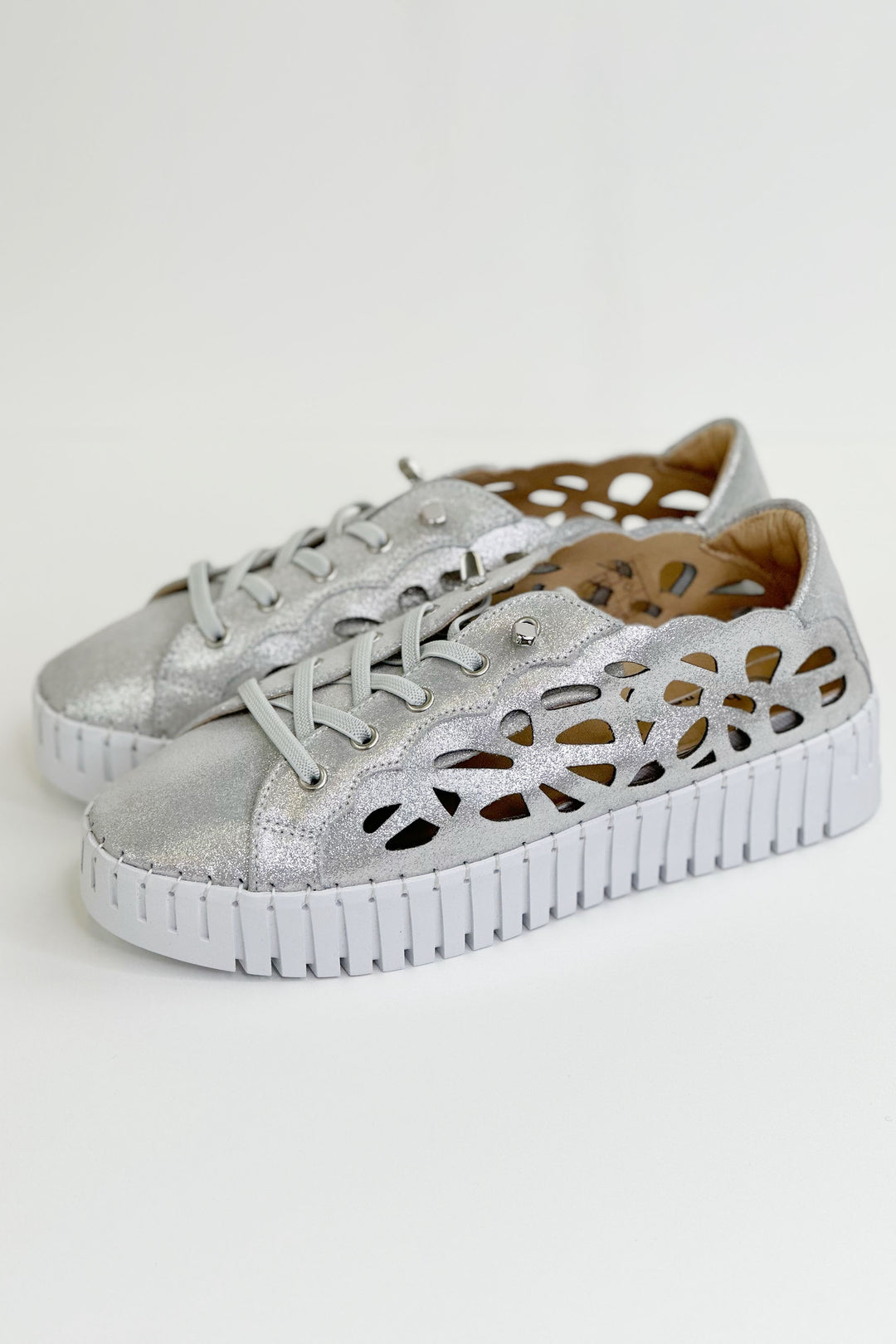 Bernie Mev Spring 2024 This stunning slip-on sneaker features a stretchy knit upper, sparkle shine finish eyelet siding design pattern, lace up details and Bernie Mev’s signature memory foam footbed.