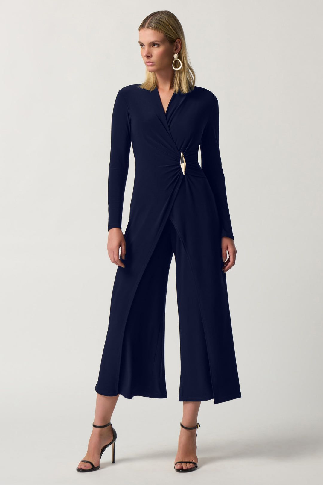 Joseph Ribkoff Fall 2024 This beautiful jumpsuit features a flattering silhouette, wide legs, and long sleeves. The broach detail adds a touch of sophistication.