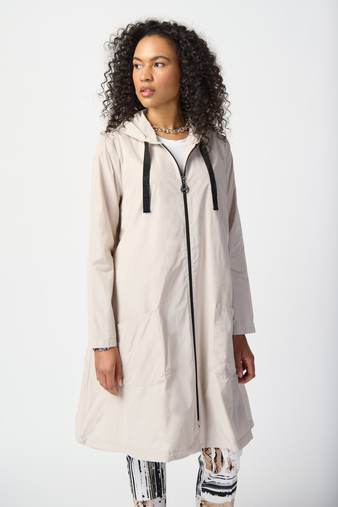 Joseph Ribkoff Summer 2024 a classic, modern and sleek design that combines fashion and function. This long coat features a drawstring hood and full front zipper for added warmth and style.