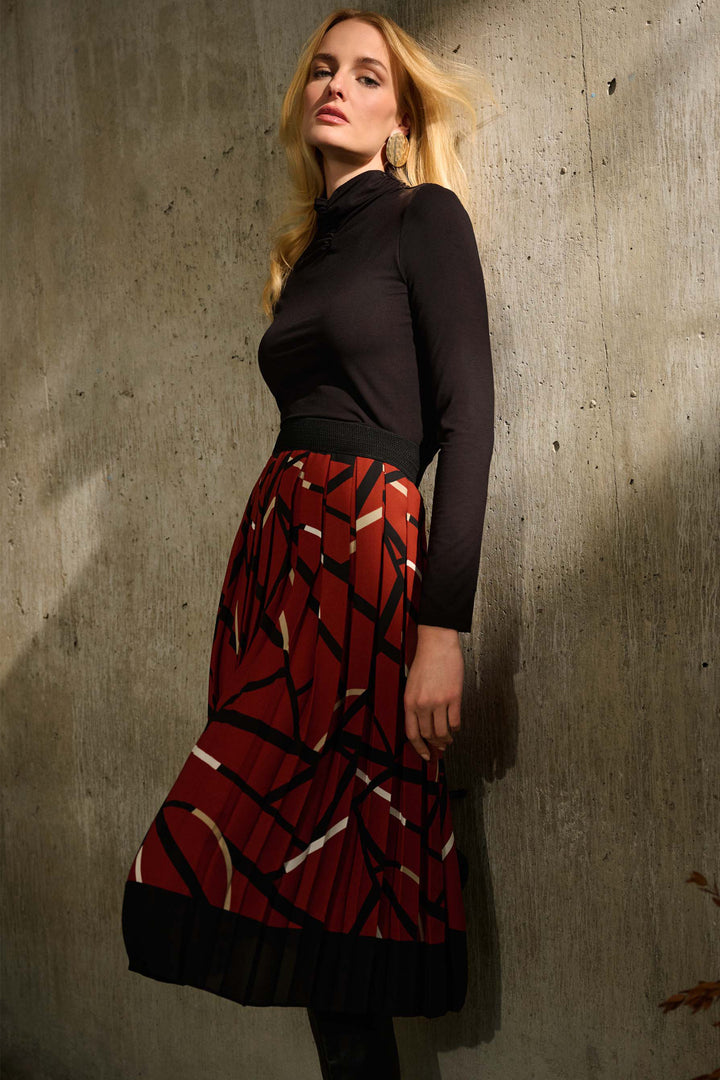 Joseph Ribkoff Fall 2024  With a high-rise waist and free-flowing pleated design, this midi-length skirt is perfect for any occasion. Its festive abstract geo print adds a touch of sophistication, making it a must-have for the holiday season. 