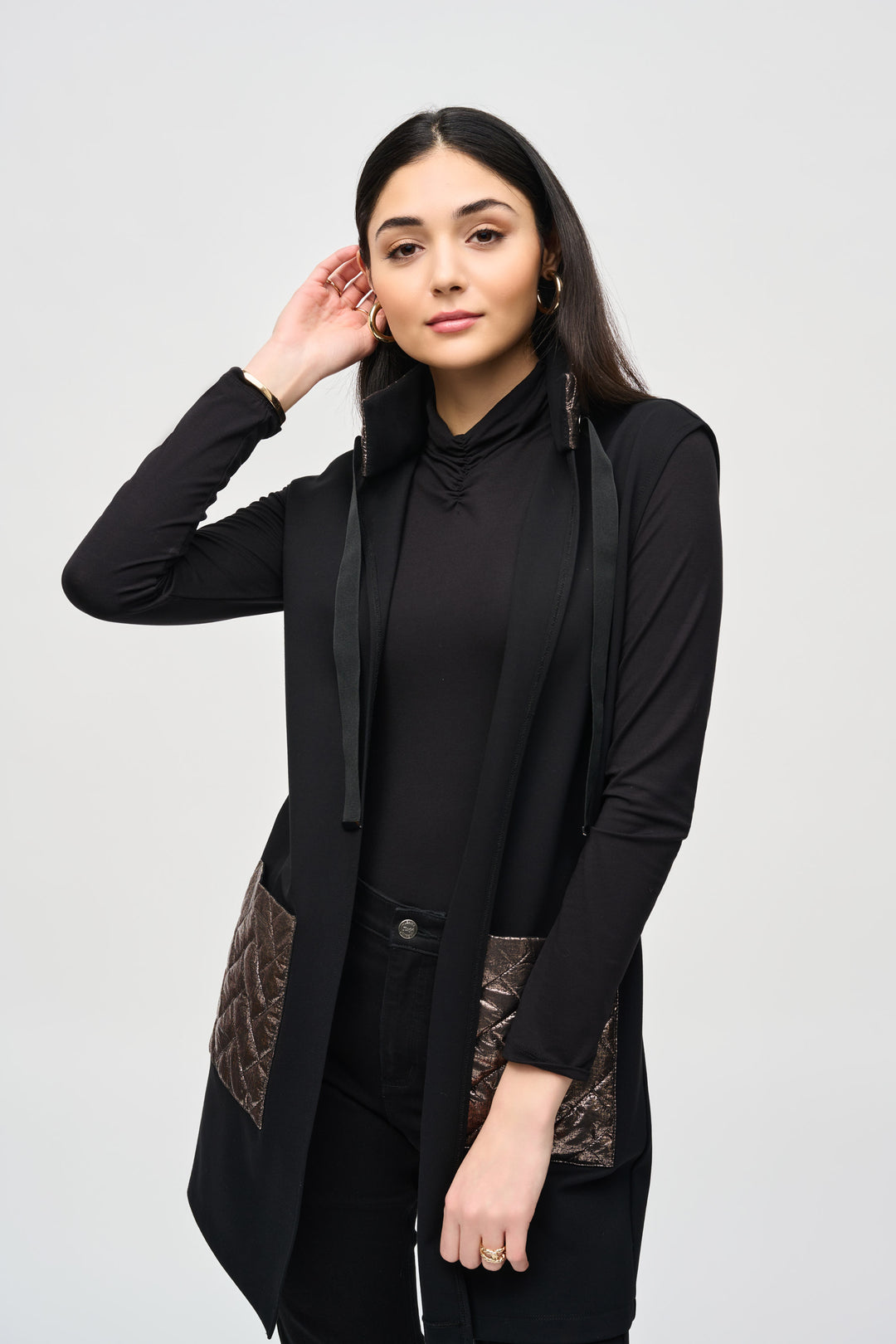 Joseph Ribkoff Fall 2024  Featuring metallic quilt front pockets, this stylish vest is both cozy and chic! With its open style and drawstring details, it's the perfect thigh-length piece for fall