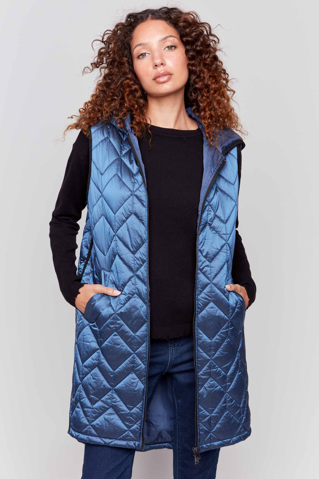 Charlie B Fall 2024  Perfect for keeping warm without compromising your style, this vest features a quilted pattern, long design with a hood and pockets that you'll love sporting all season long! 