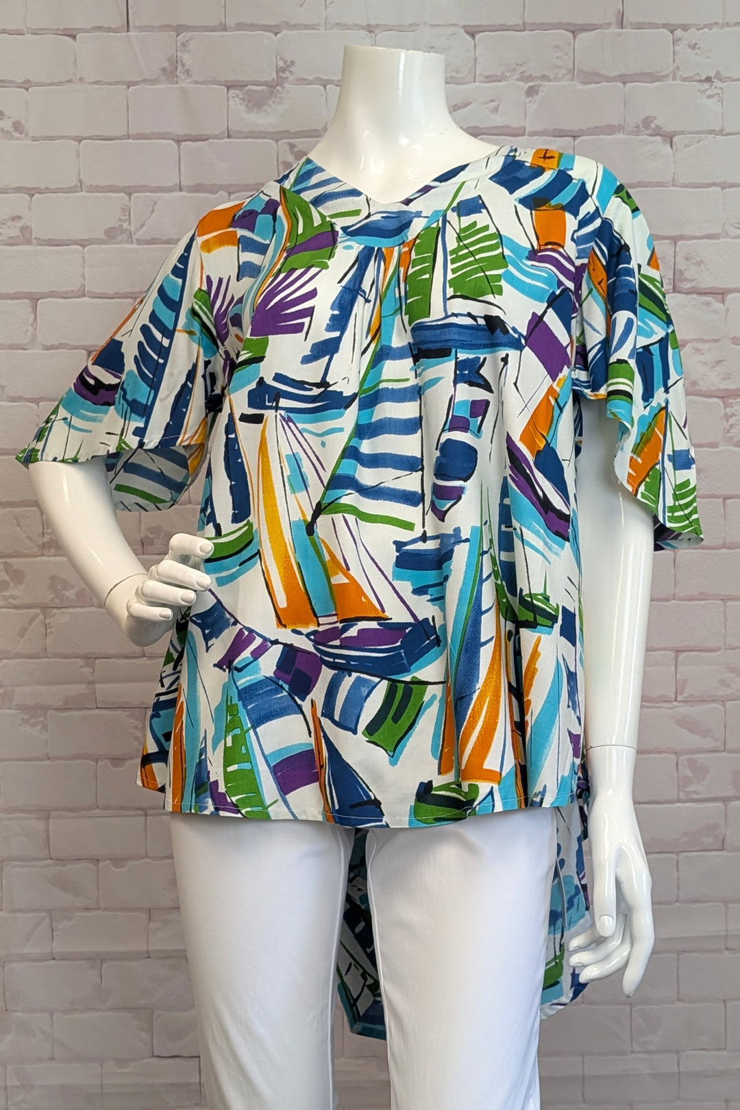 ORIENTIQUE Spring 2025 This vibrant, abstract sailing print tunic features a flattering v-neck and high-low hem, making it the perfect addition to your wardrobe.